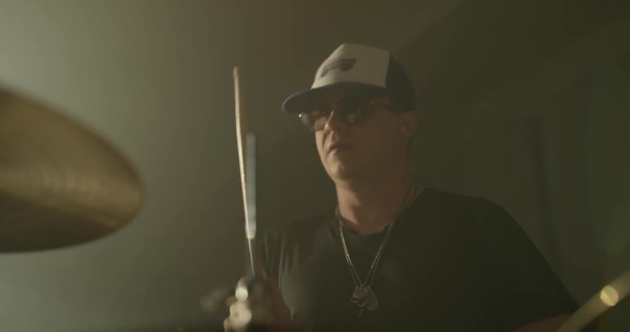 Close up of symbols and drums being played with drummer in background