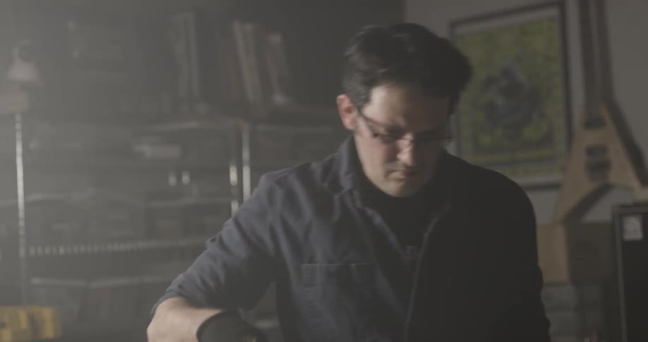 Man uses vacuum around guitar on table