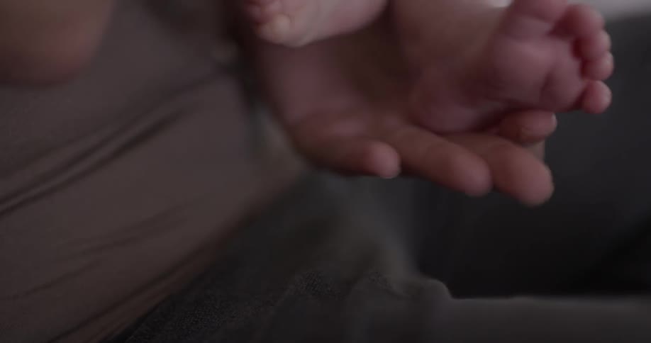 Someone holds a babies feet as the baby wiggles
