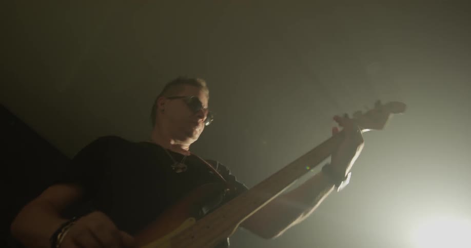 Man plays guitar in room with bright light
