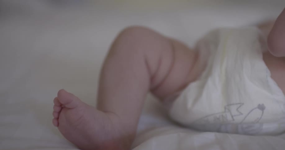 A baby laying in a bed kicking their feet up