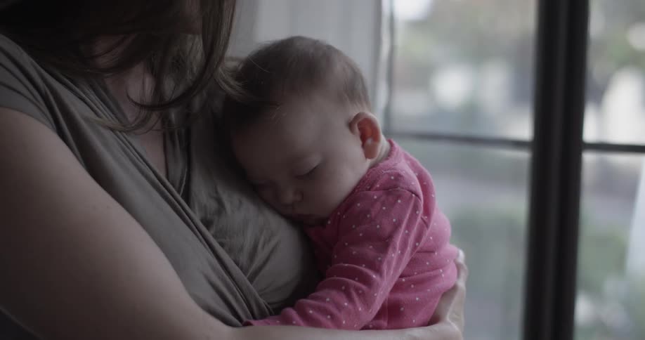 Mother holds sleeping infant against chest