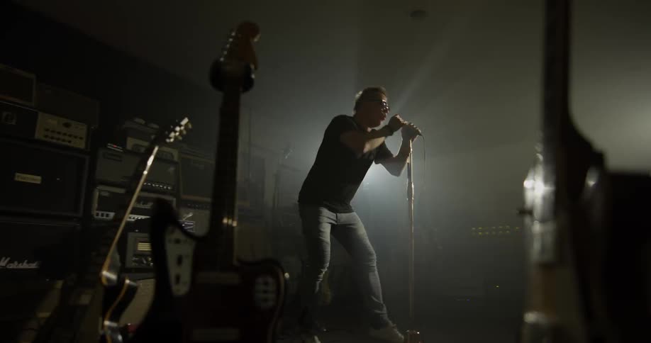 A man sings into a microphone in a dark room
