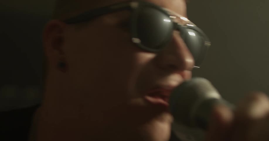 Man with sunglasses sings into microphone