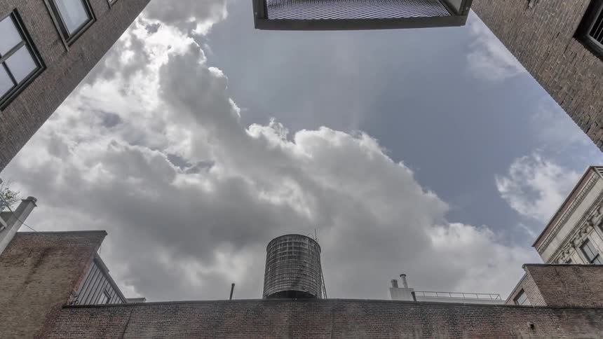 Fluffy clouds move past a building
