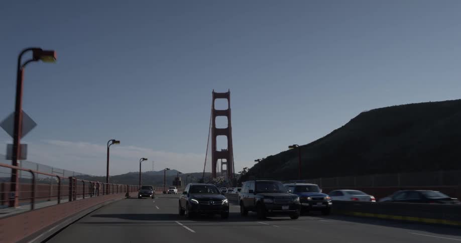 Cars drive down a highway with a bridge in the distance