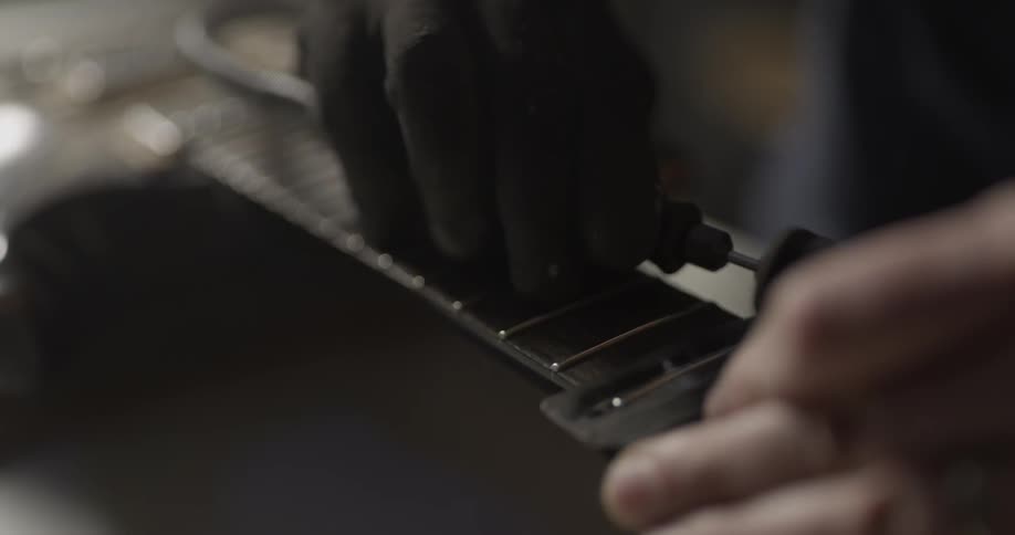 A man is putting strings on a guitar