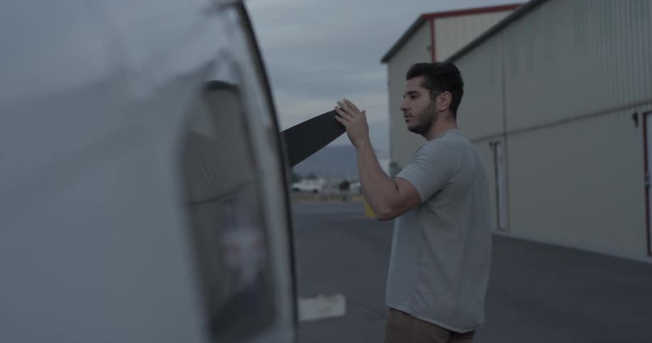 Man walks up to a plane and inspects parts at an airplane hangar