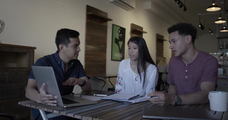Two men and a woman discuss something on a computer screen