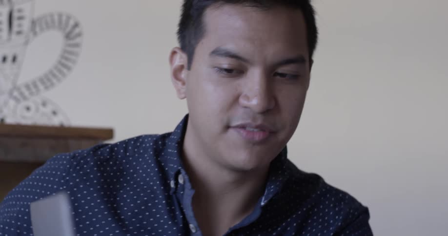 A man points at a laptop's screen and talks