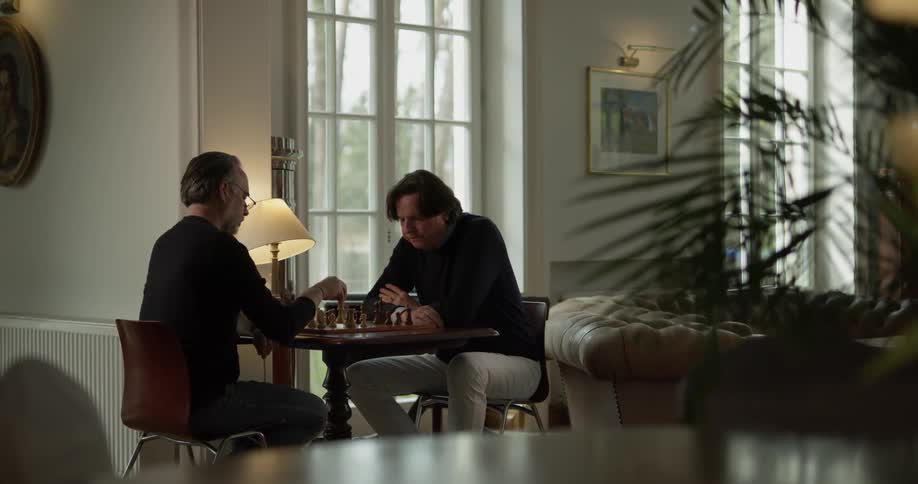 Two men sitting at a chess table playing chess