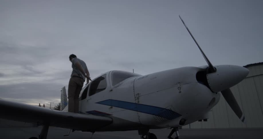 Man exits propeller plane and jumps down to pavement