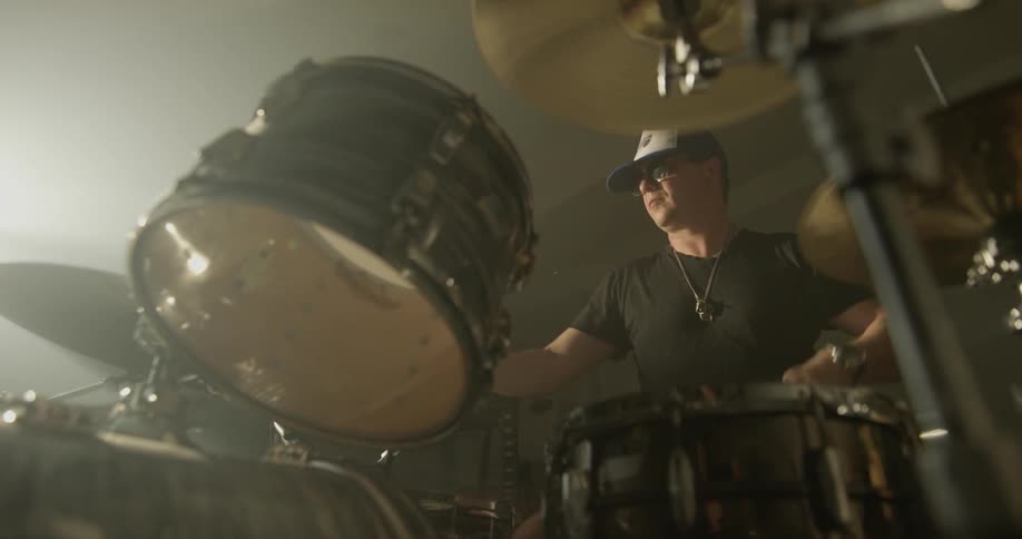 Man plays drums in brightly lit room