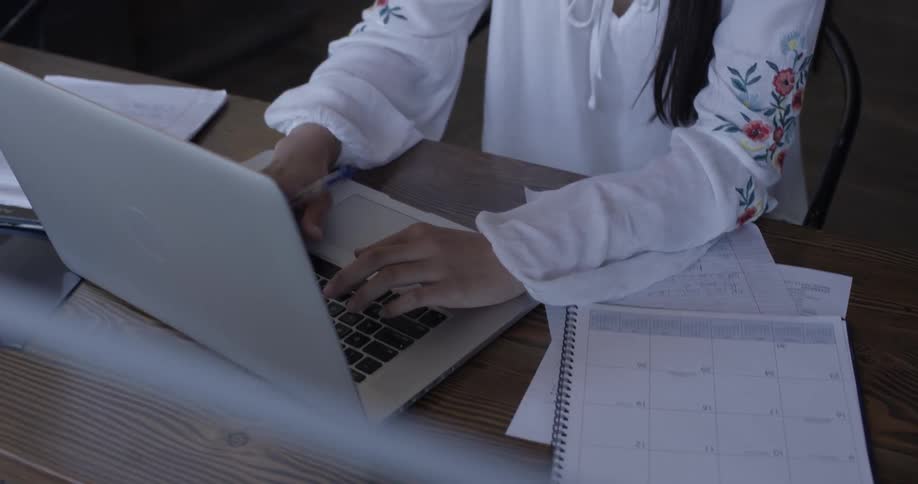Woman types on laptop at desk