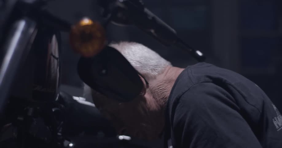A man is sitting beside a motorcycle