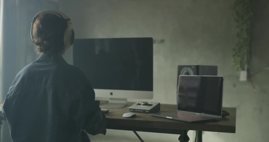A person is looking at a computer and putting headphones on