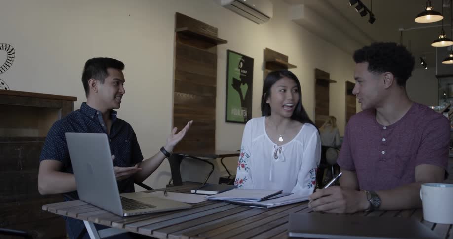 A man shows another man and a woman something on a laptop screen