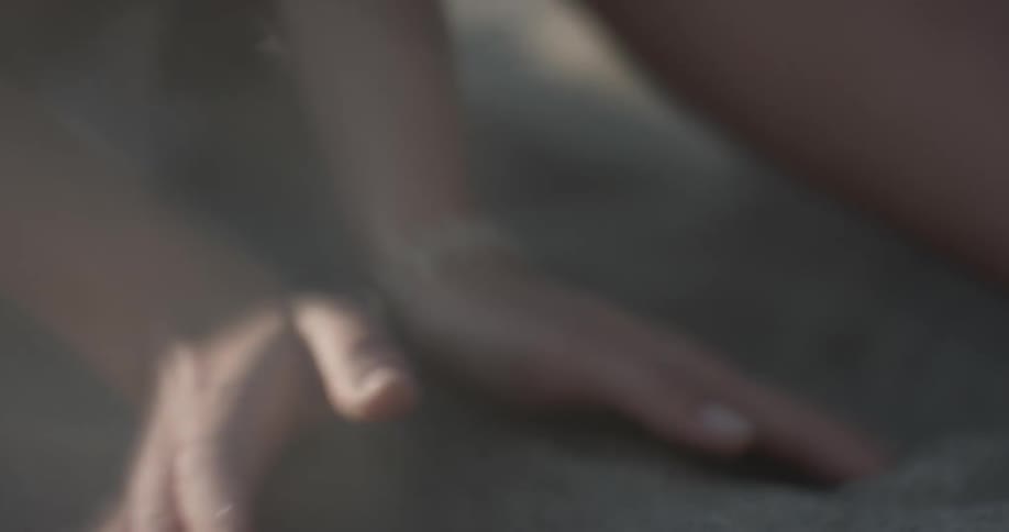 A young lady scoops dirt up in her hands and lets it sift back onto the ground