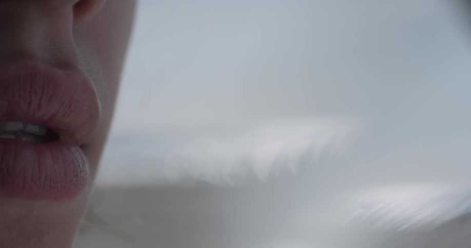 A woman sitting on the beach parts her lips