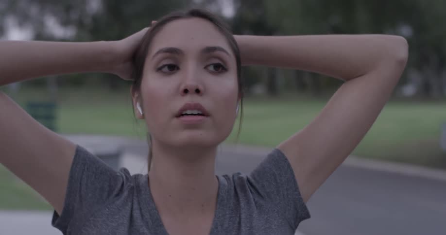 A woman with headphones in at a park