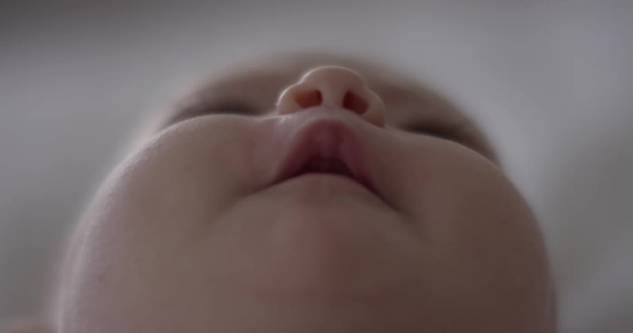 An infant laying on its back looking to the ceiling