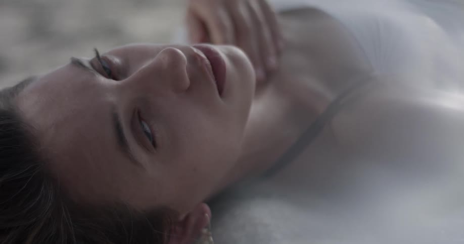 Woman lying on the ground rubs her throat and looks up at you