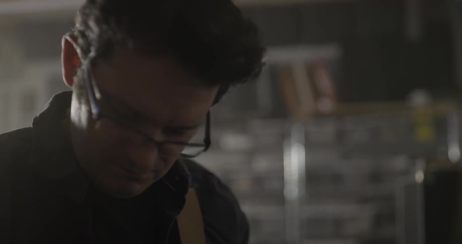 Man looks down at guitar he's playing off screen