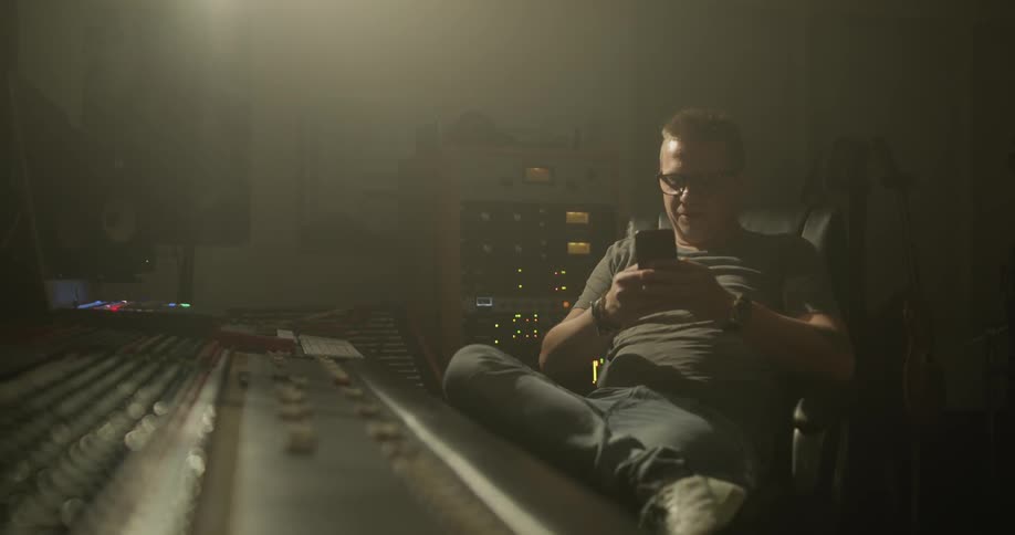 Man looking at his phone in front of a sound board
