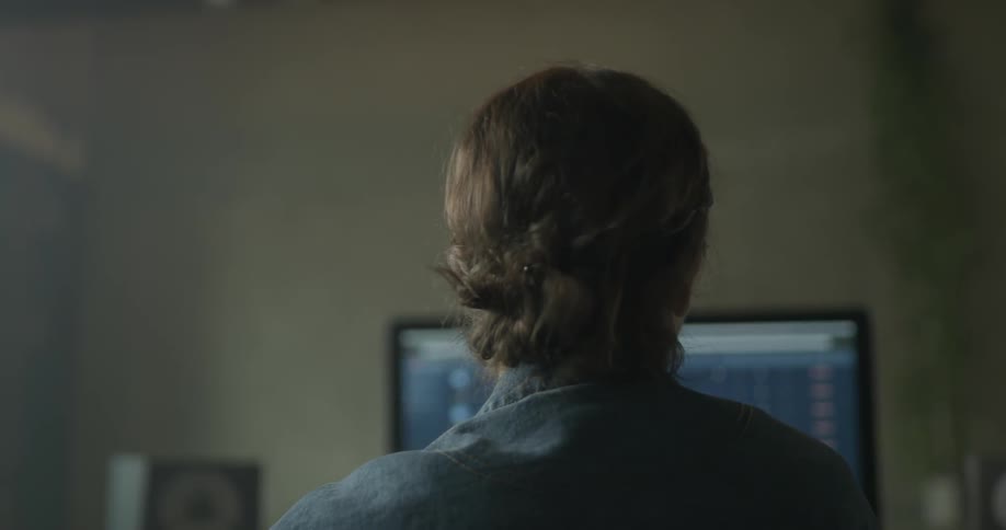 A woman removes headphones while using computer