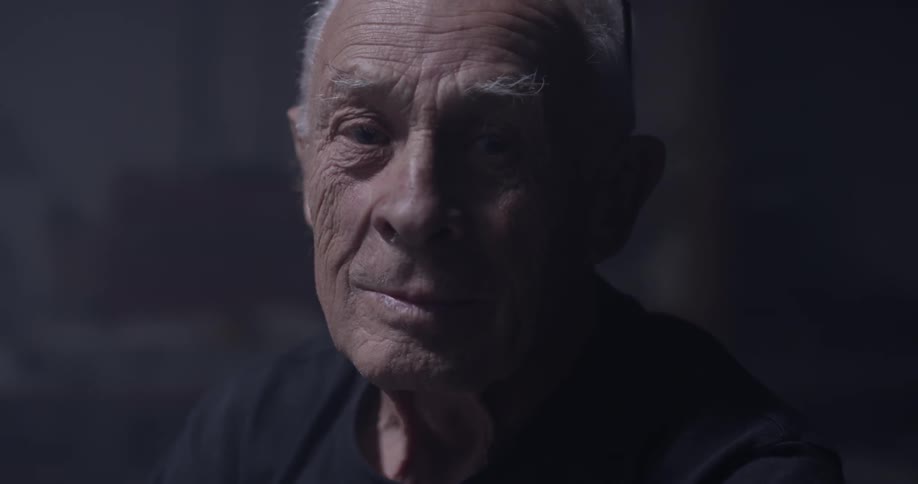 An elderly man lifts his head