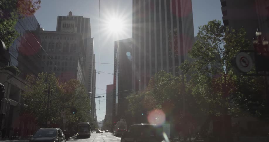 Suns shines brightly between skyscrapers along road