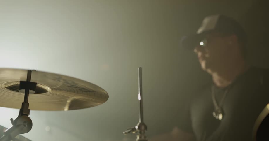 Man plays drums in brightly lit room