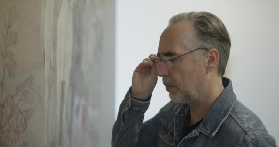 A man is looking at paintings in a room