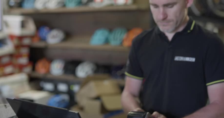 Worker checking out a customer paying with credit in a bike shop