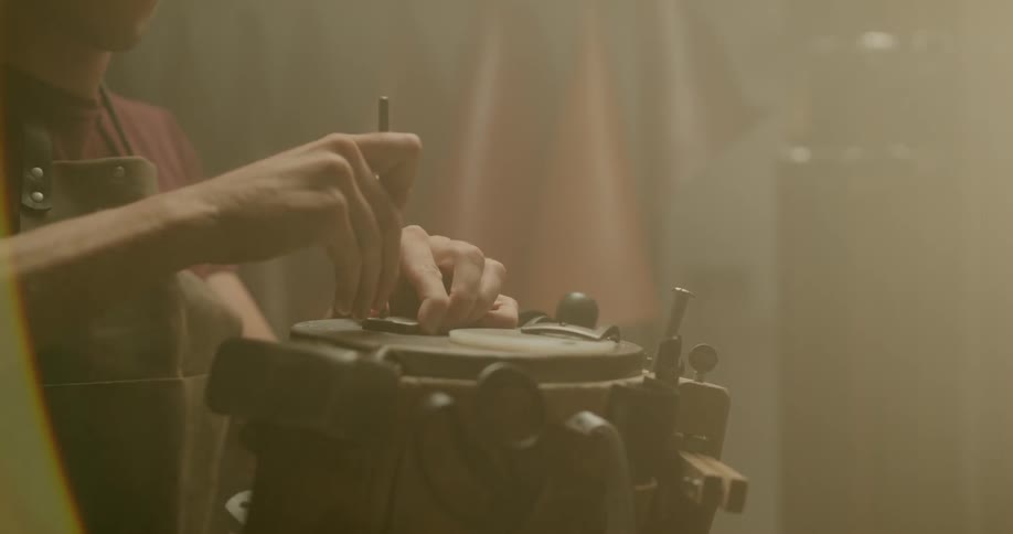 A craftsman is using an awl to stamp a piece of leather