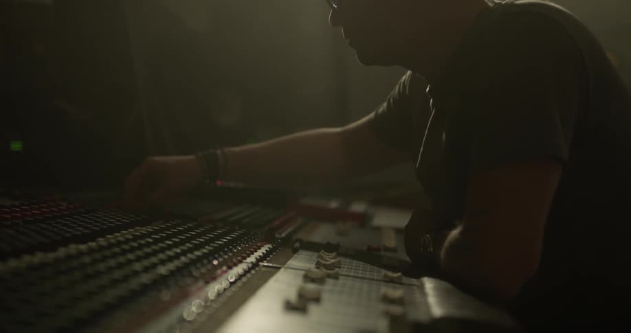 Man in dimly lit studio presses buttons