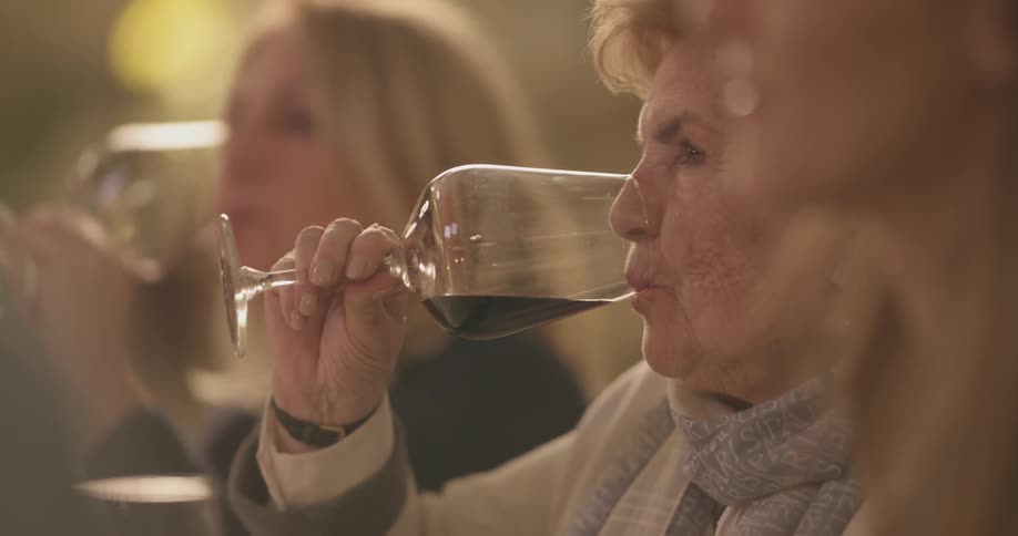 Women take sips of wine as they dine together