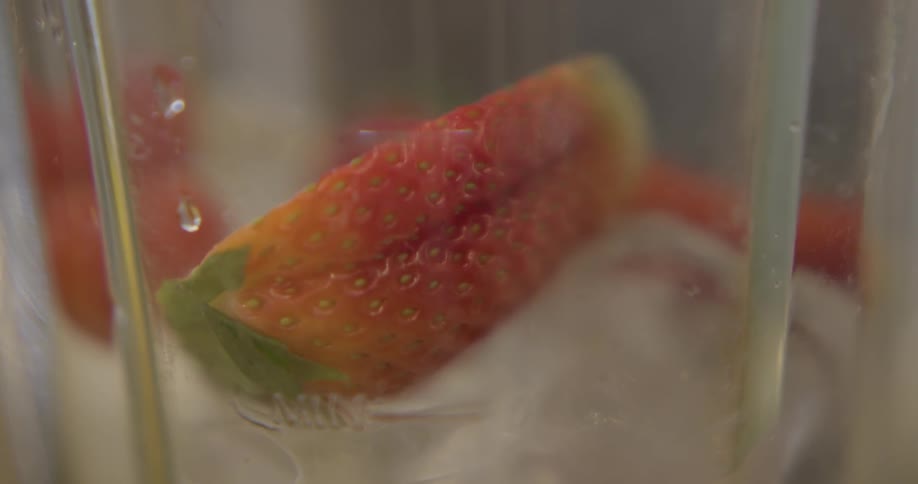 A strawberry is placed into a glass