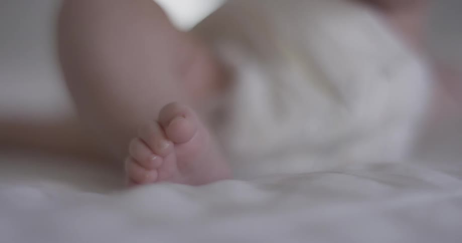 A baby rolls around and moves its feet