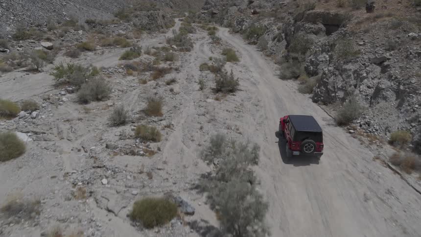 A jeep drives over a dirt road in the desert