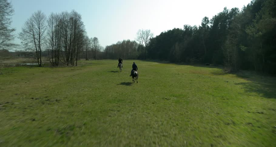 Two people are riding horses outside