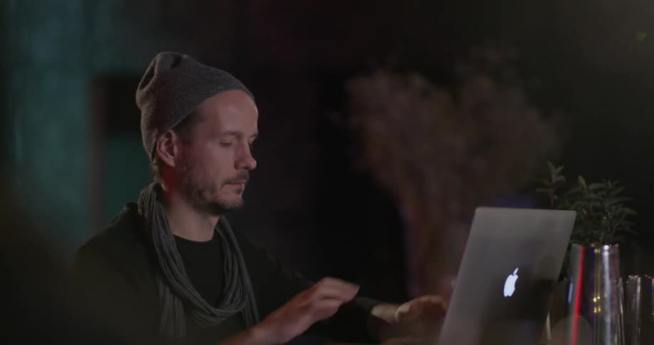 A man sits down and opens a laptop