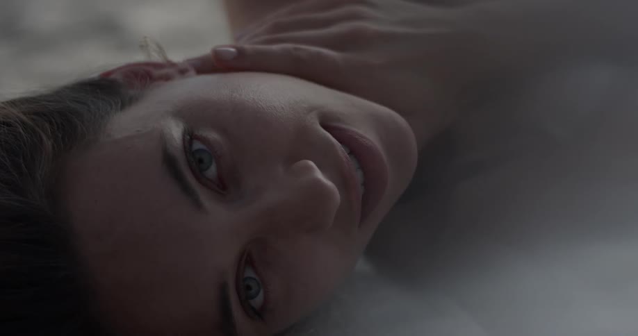 Woman lays on her back and turns to to the side