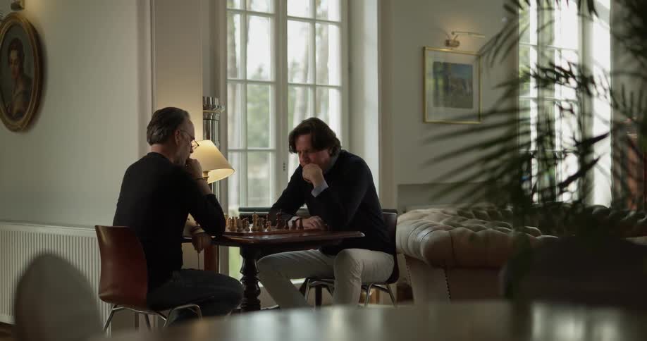 Two men are playing chess inside a club in daylight