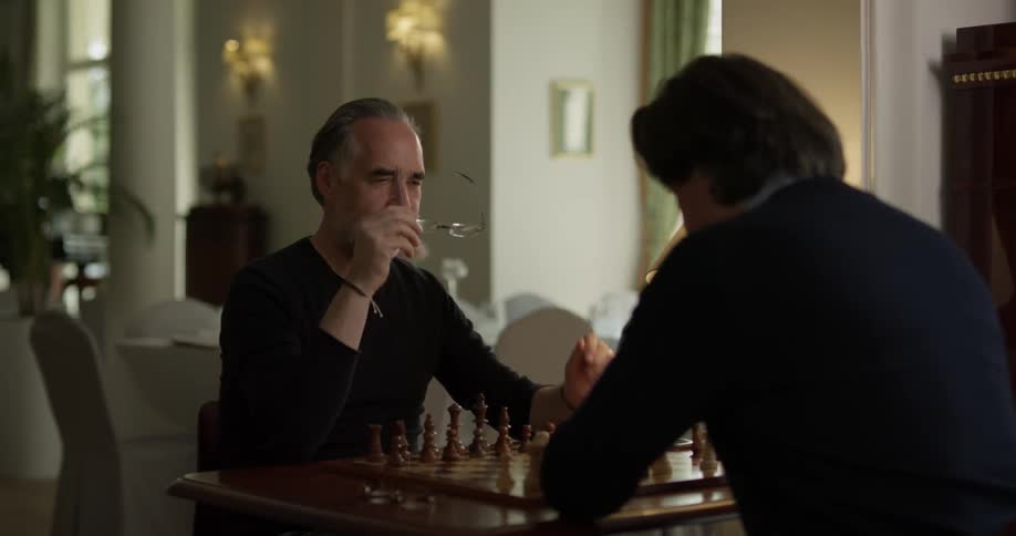 Two men sitting at a chess table having a conversation