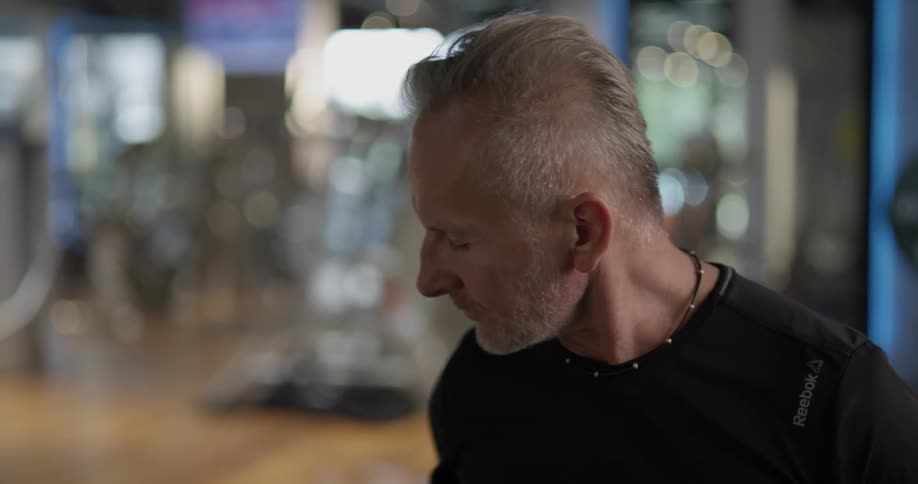 Man at gym looks over his cellphone before taking a sip of water