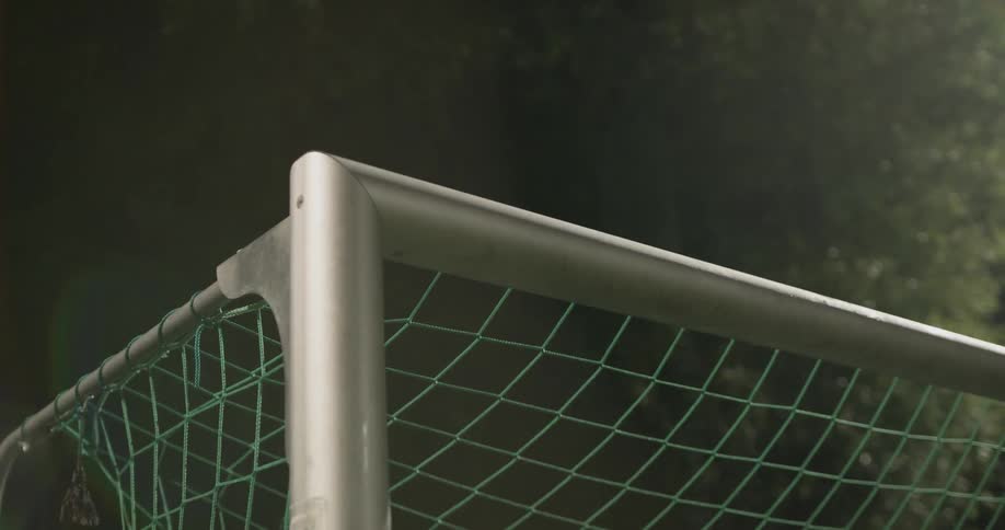A soccer net that is out on a field at night