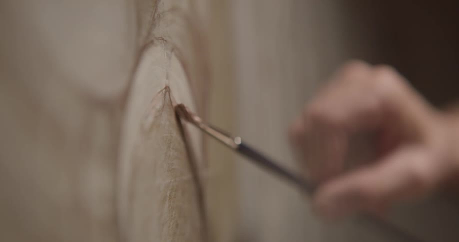 An artist gently dabs a paintbrush on to the canvas