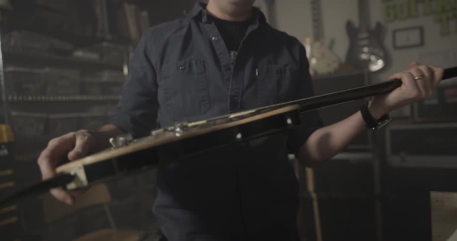 Man looking at electric guitar and sets it down