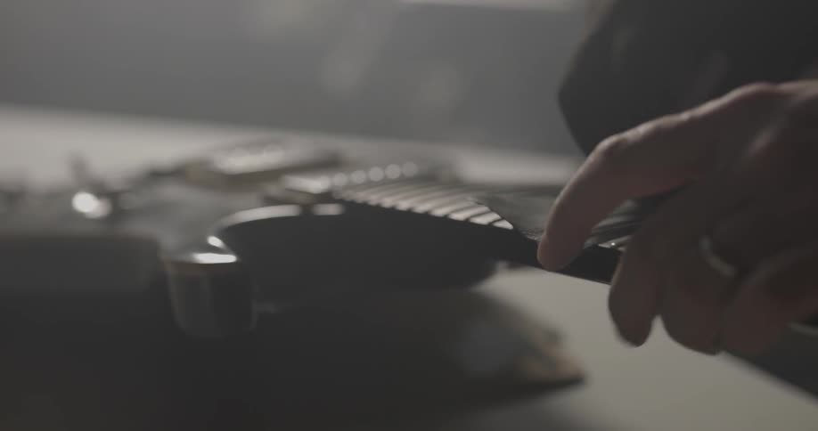 A man uses a tool on an electric guitar